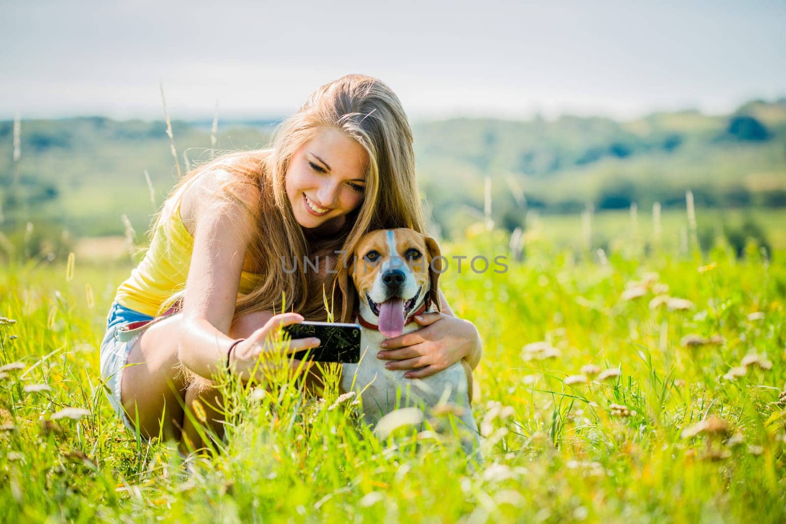 Young woman taking photo of herself and her pet with mobile phone camera