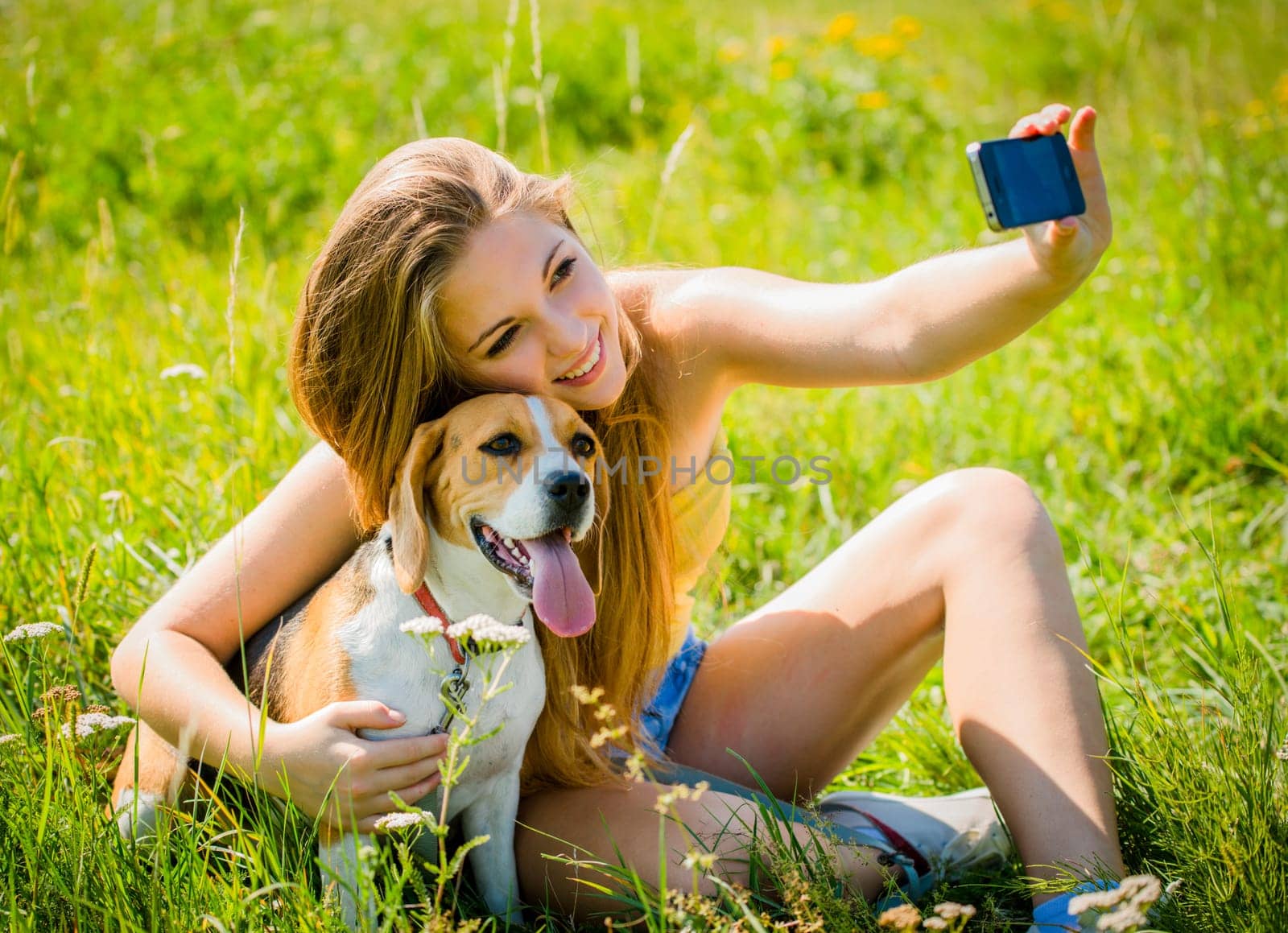 Teen girl taking photo of herself and her dog with mobile phone camera