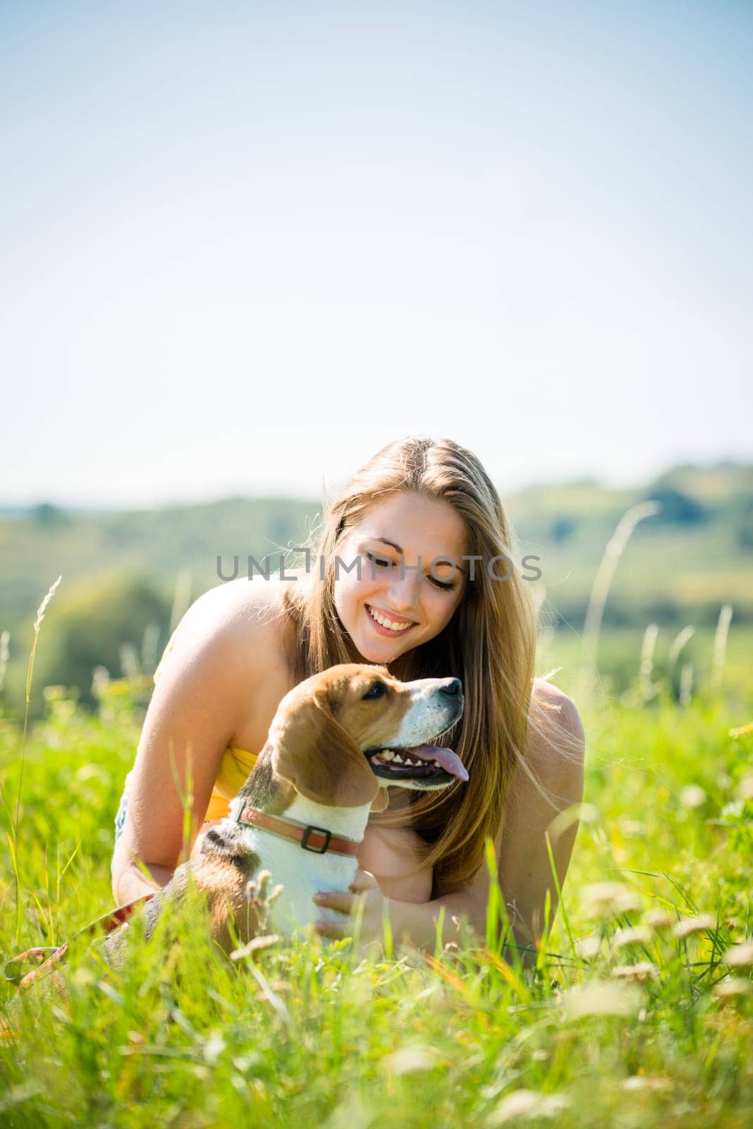 Lifestyle photo of happy young girl with her pet (beagle dog) - outdoor in nature