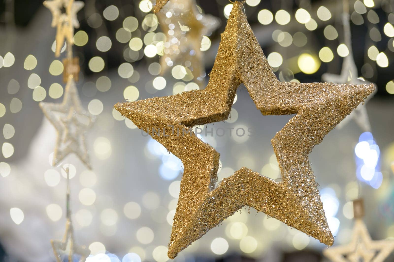 Hanging golden star Christmas decoration on blurred background