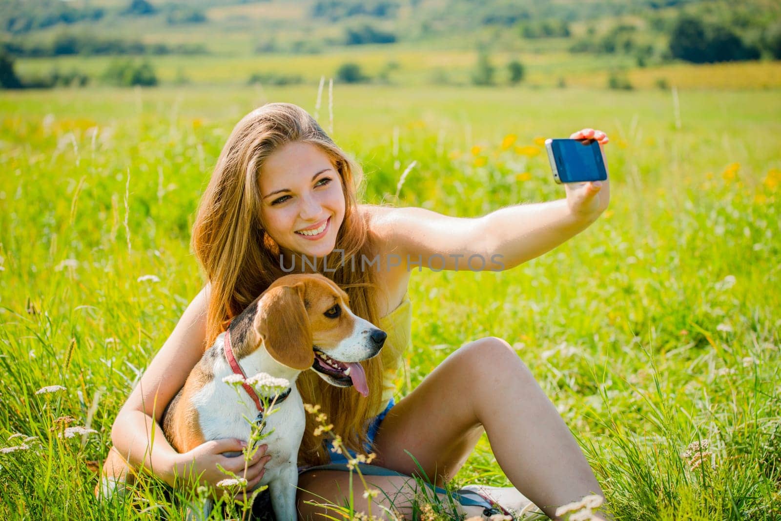 Young woman taking photo of herself and her pet with mobile phone camera