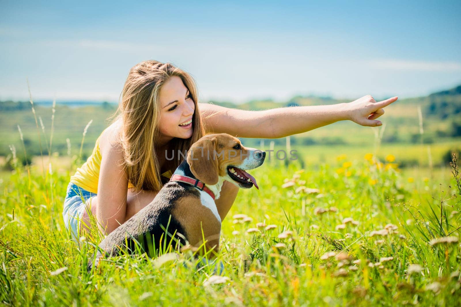 Young woman (teen girl) showing her dog with hand - outdoor in nature