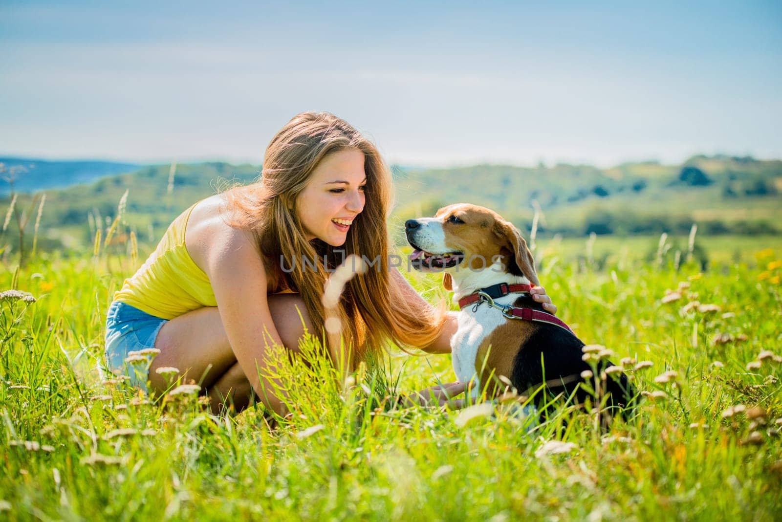 Lifestyle photo of happy young girl with her pet (beagle dog) - outdoor in nature