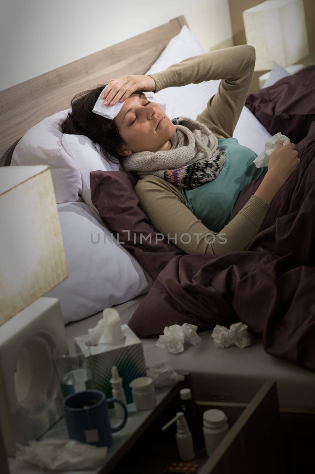 Sick woman with flu lying in bed suffering from headache