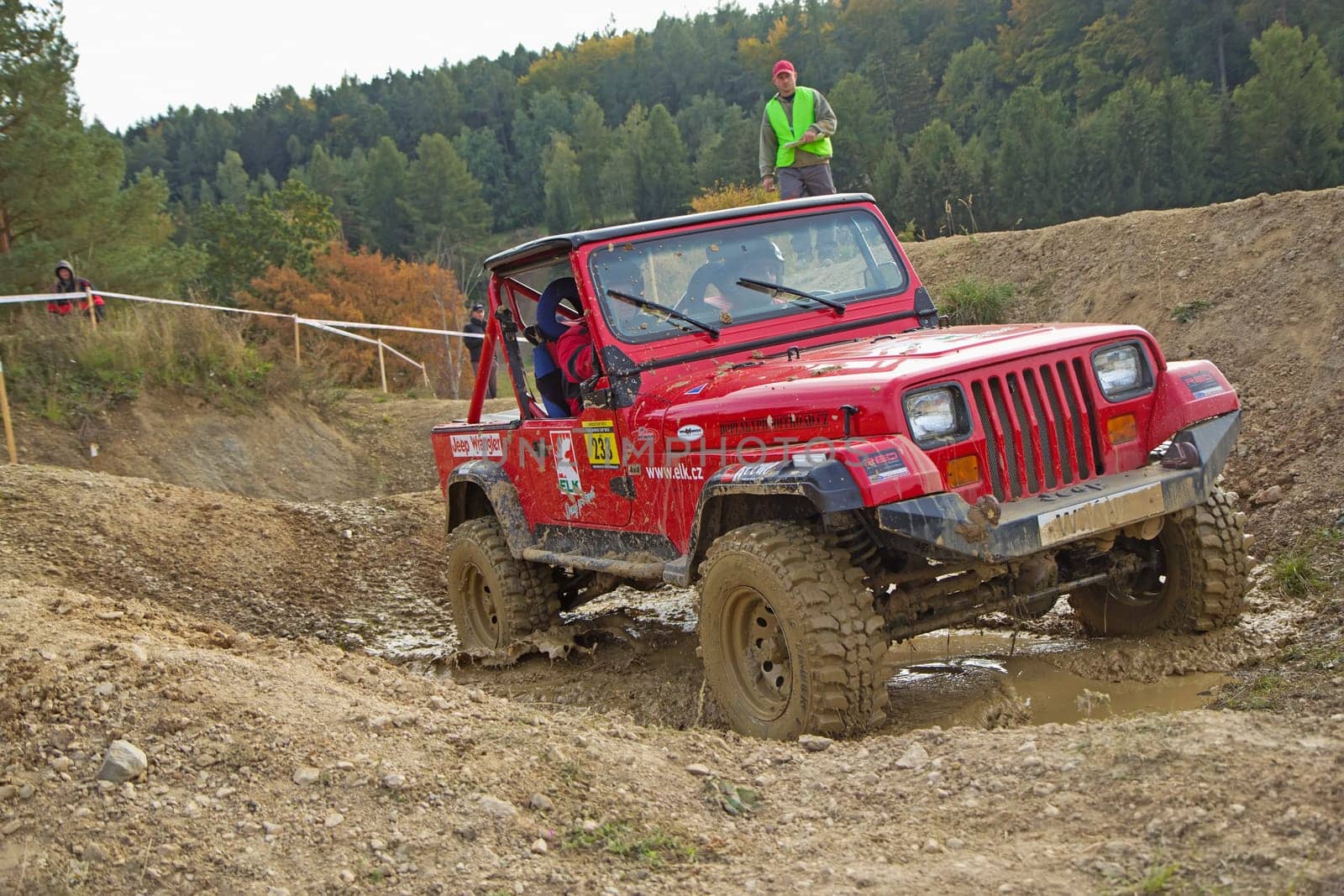 MOHELNICE, CZECH REPUBLIC - OCT 05. Red car is passing through  a puddle of mud on a trial race in the "BIG SHOCK CUP Trial 2013"" on October 05, 2013 in Mohelnice, Czech Republic."