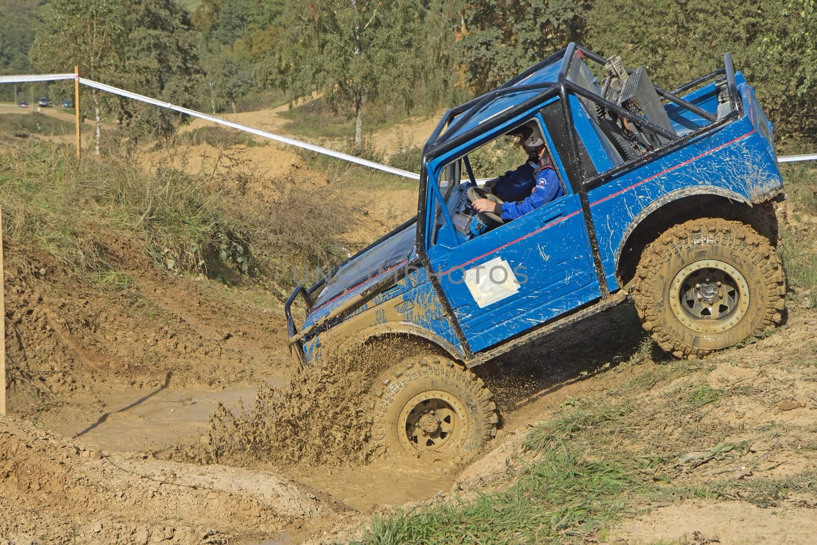 MOHELNICE, CZECH REPUBLIC - OCT 05. Blue car is entering into  a puddle of mud on a trial race in the "BIG SHOCK CUP Trial 2013"" on October 05, 2013 in Mohelnice, Czech Republic."