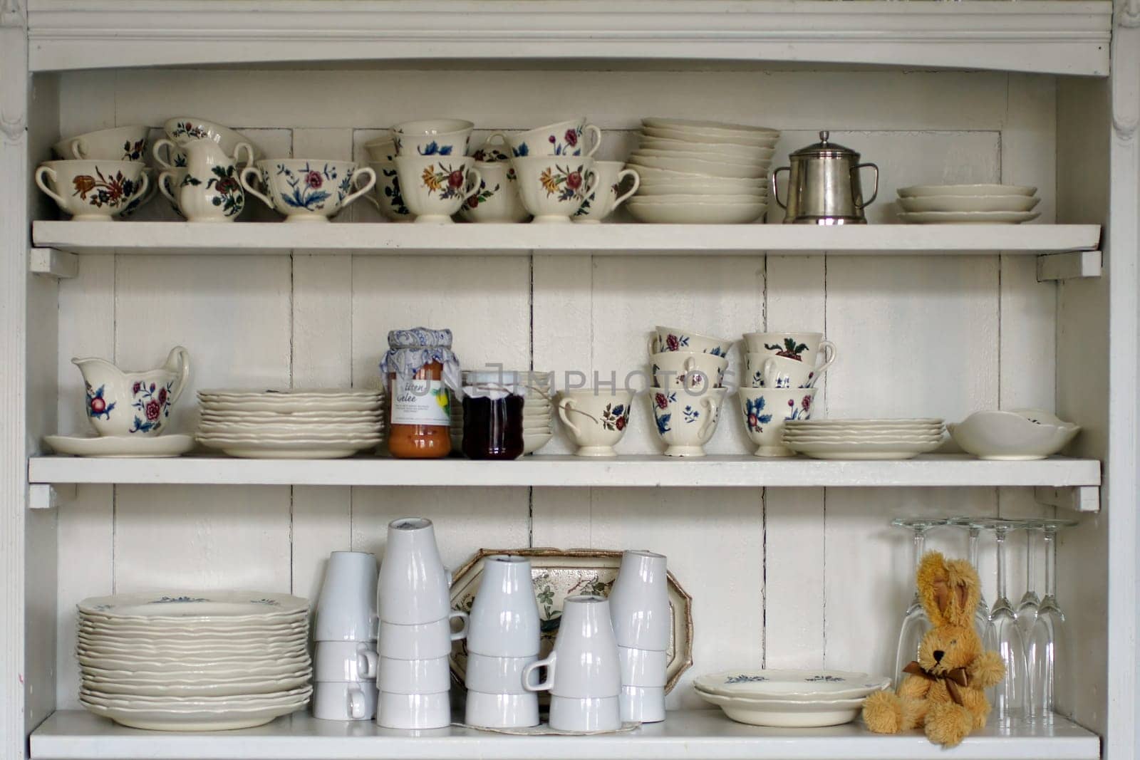 The photograph of an old kitchen shelf with cups and plates.