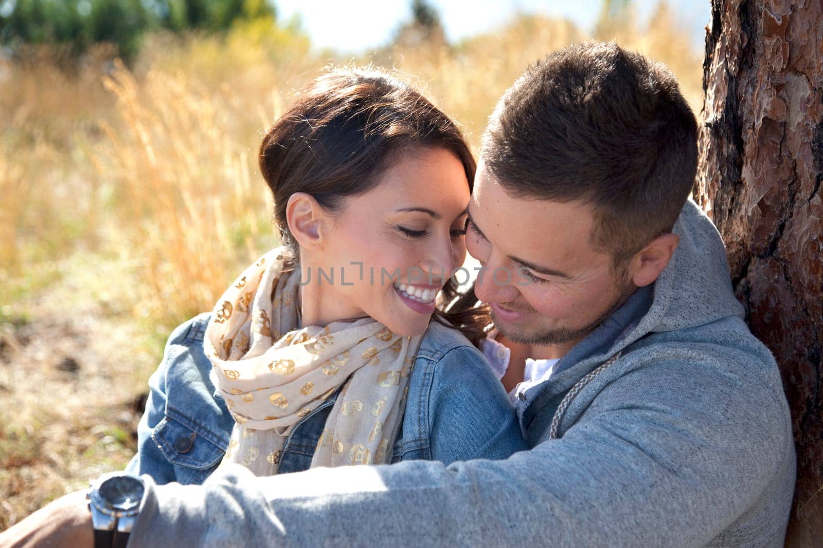 Outdoor close-up photo of young couple seated in grassy field.
