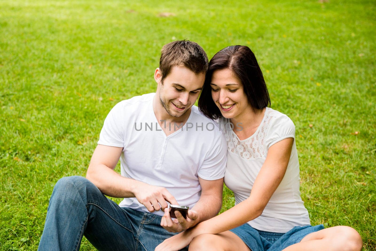 Young happy couple looking on mobile phone - outdooor in nature