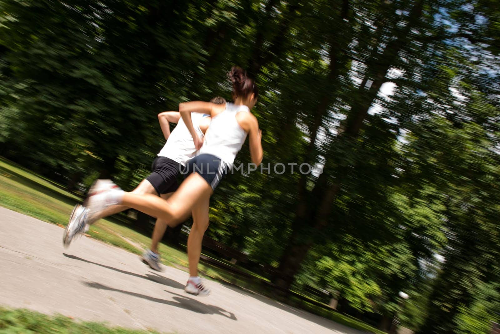 Young man and woman jogging outdoor in nature - motion blur image (panning)