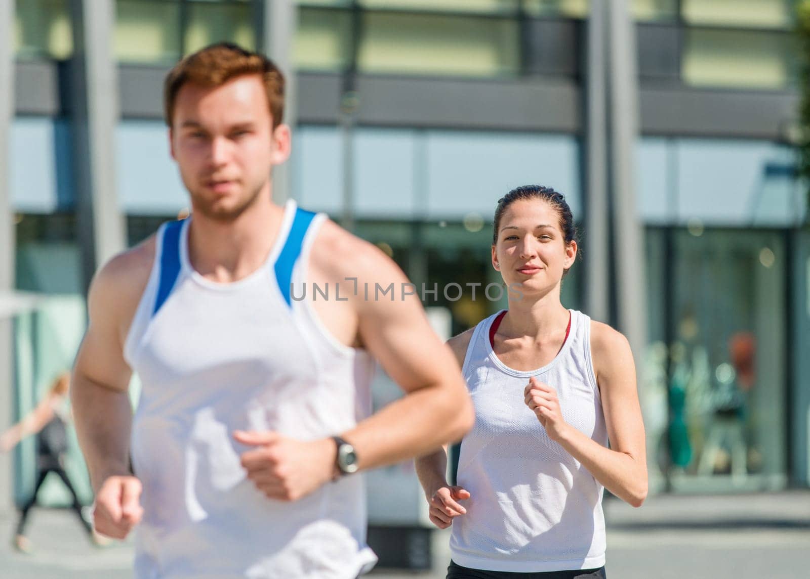 Young sport couple jogging in city environment - focus on woman