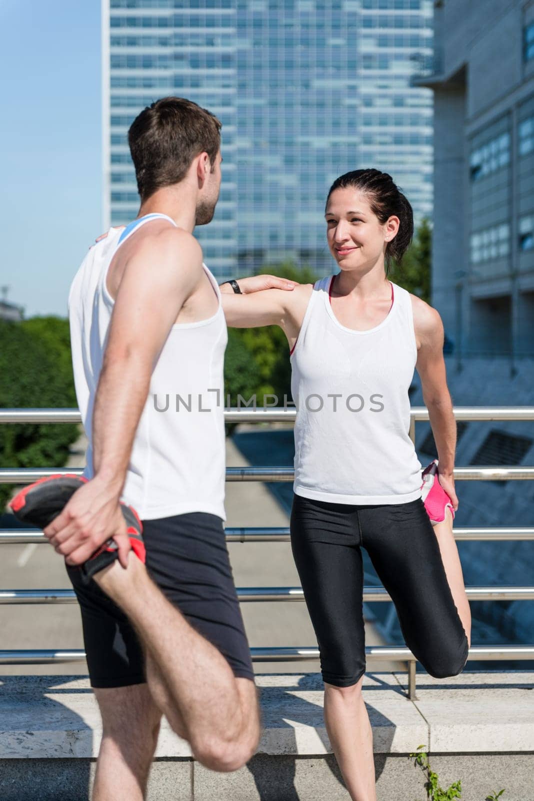 Couple exercising and stretching muscles before sport activity in city