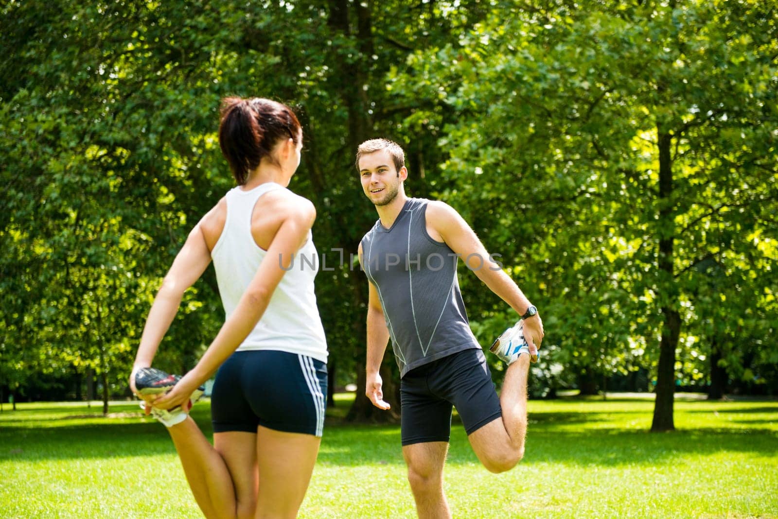 Young couple exercising and stretching muscles before sport activity - outdoor in nature