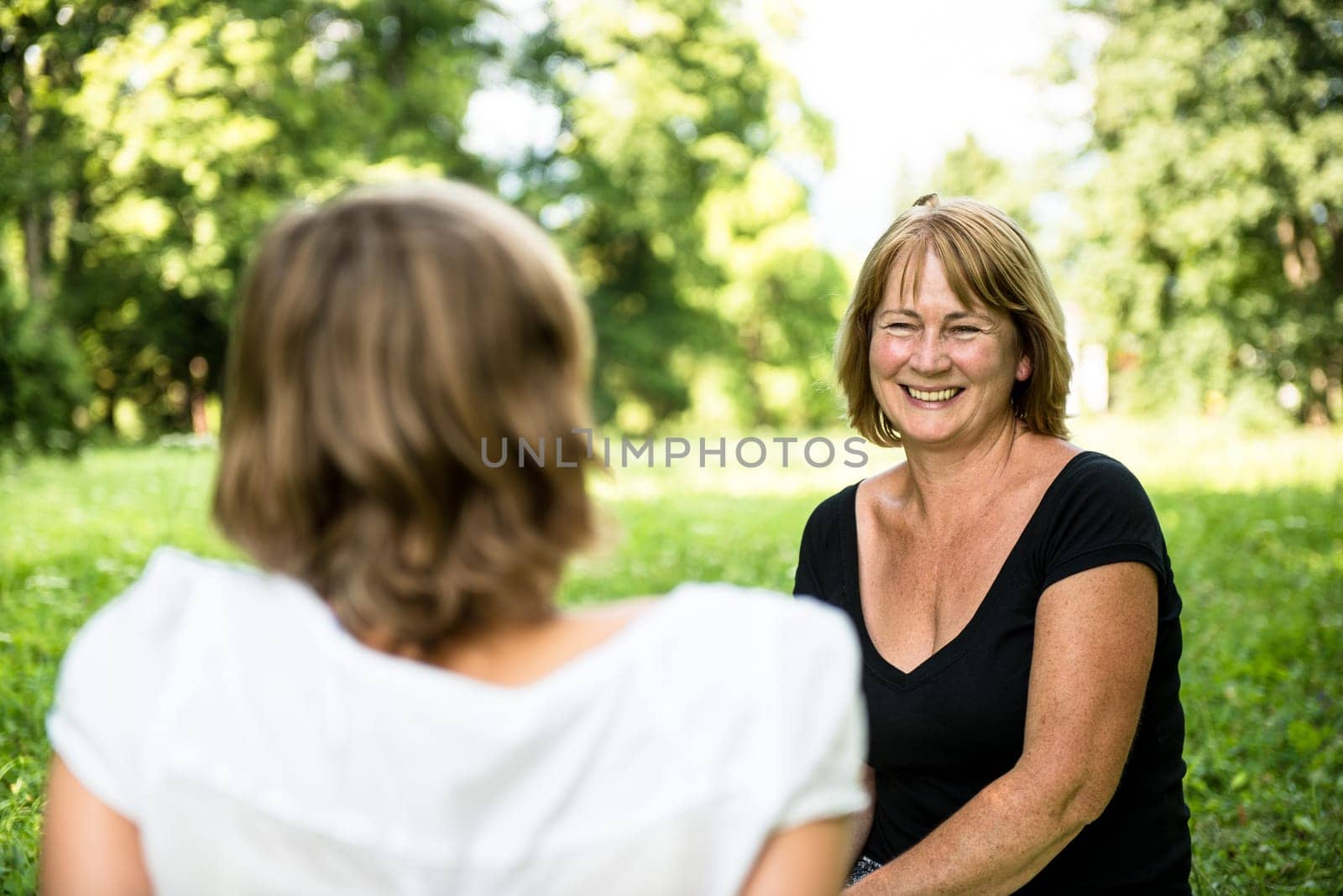 Senior woman chatting with her adult daughter outdoor in nature
