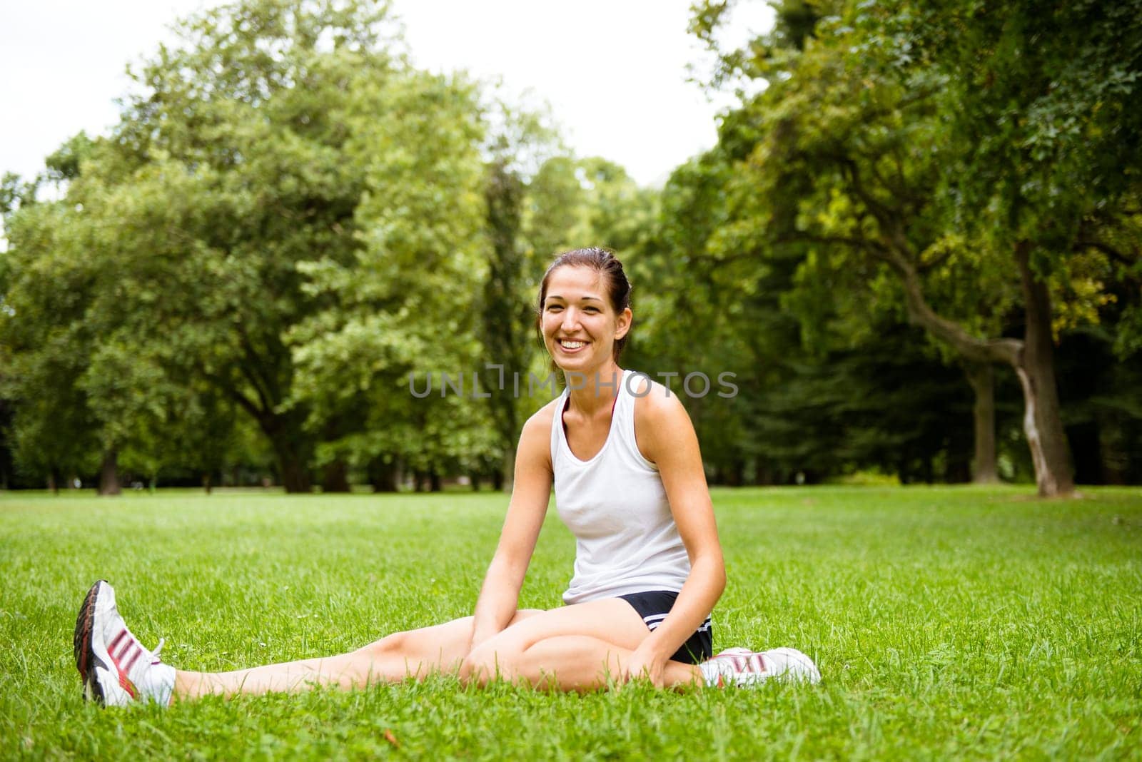 Young smiling fitness woman stretching muscles before sport activity