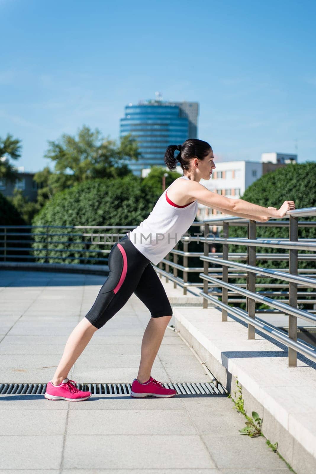 Young sport woman is stretching leg before jogging - outdoor in city