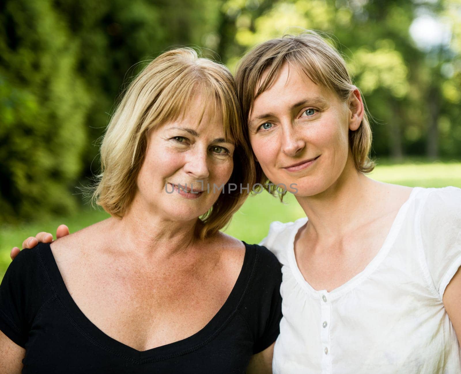 Outside portrait of smiling happy mature woman with her adult daughter