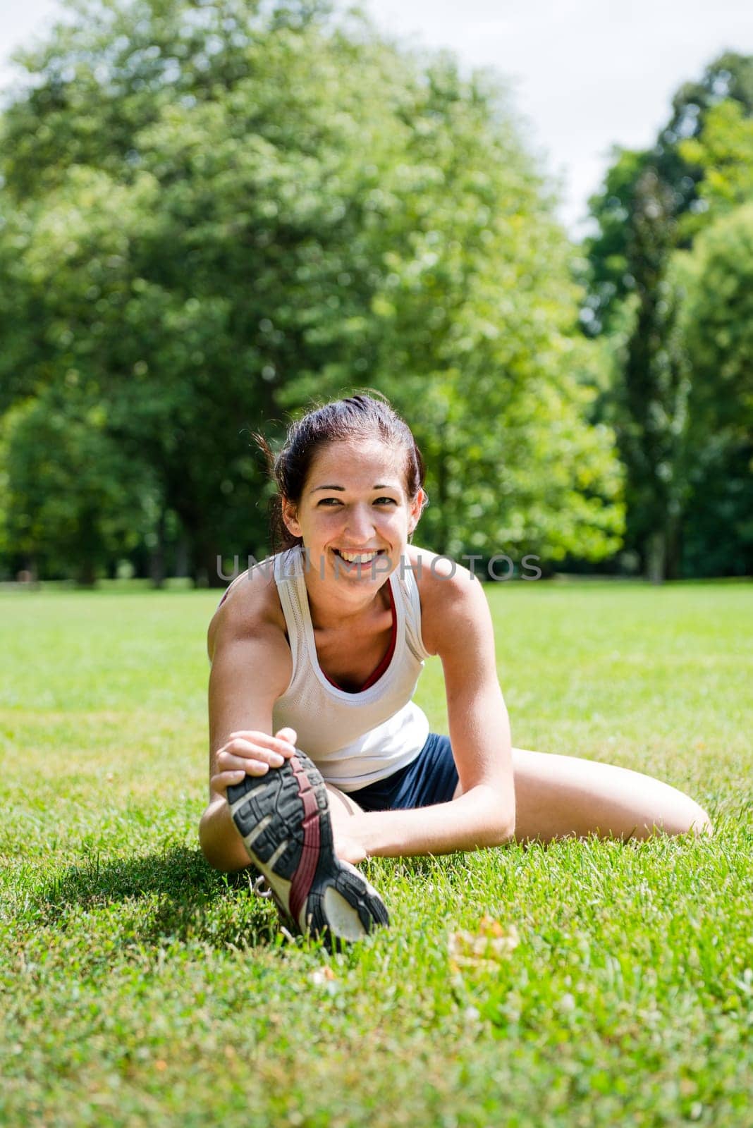 Young fitness woman stretching muscles before sport activity - outdoor in park