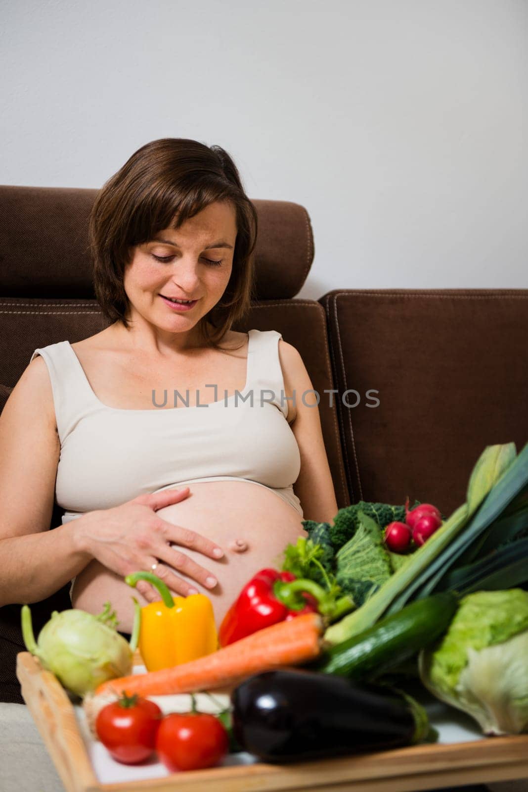 Lifestyle portrait of pregnant woman with vegetables in home kitchen