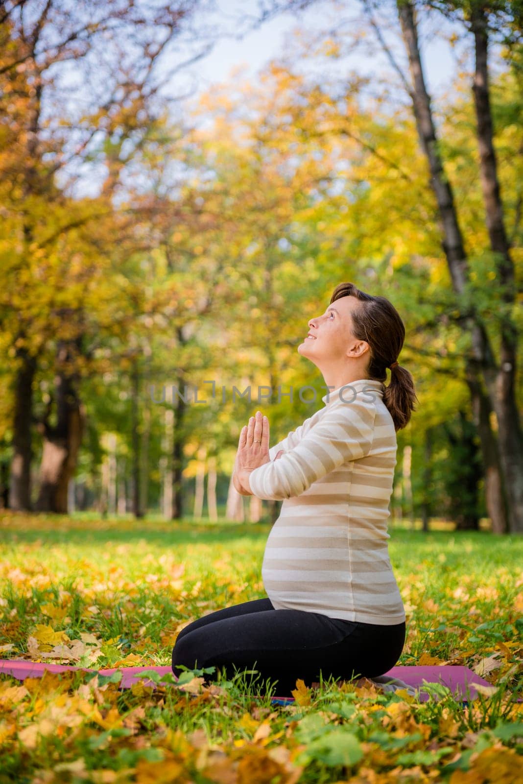 Happy pregnant woman giving thanks to god in autumn beautiful nature