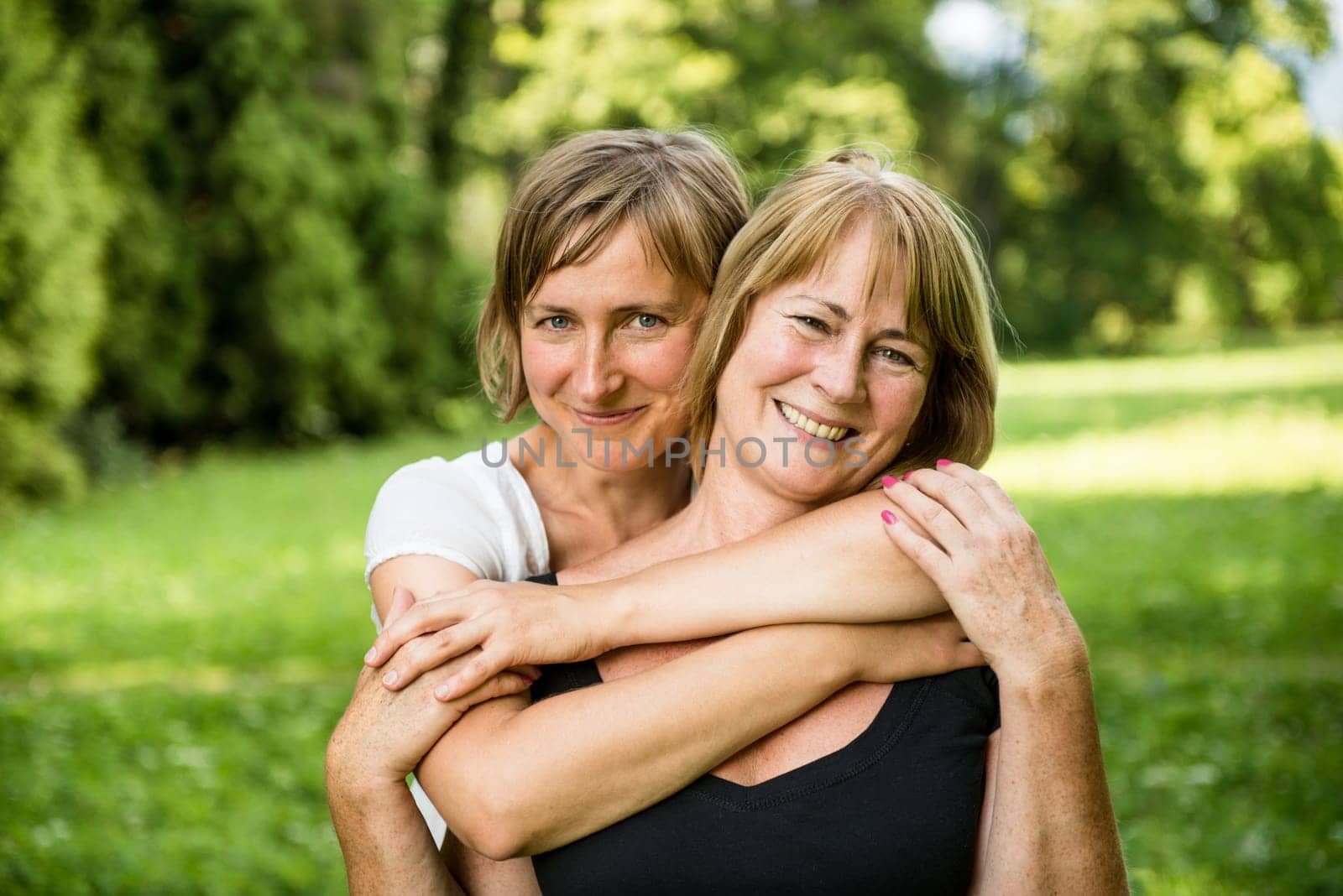 Outdoor portrait of smiling happy senior mother with her adult daughter