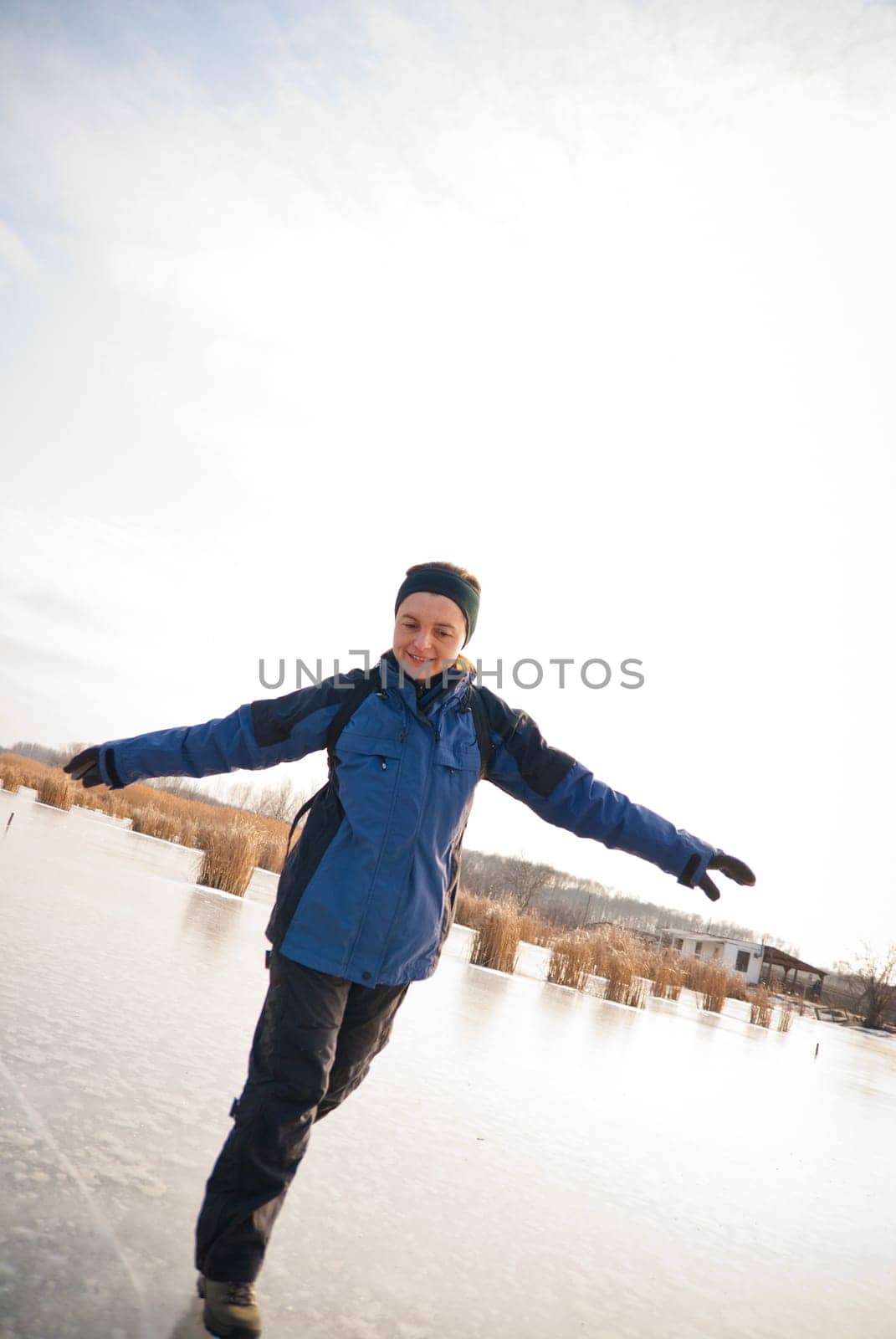 Young smiling woman is sliding on ice - winter outdoor scene