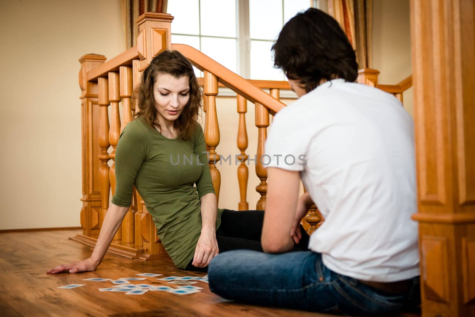 Young couple playing cards together in home - wooden interior