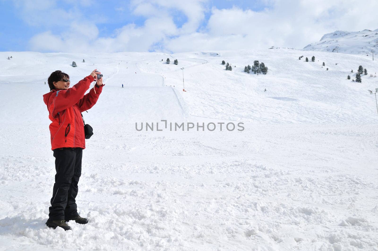 Senior woman taking picture with camera in mountain winter snow landscape
