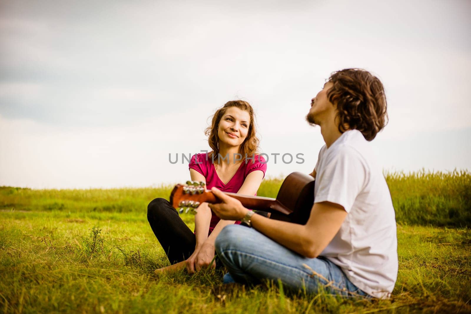 Dating couple - young man playing to his girlfriend on guitar