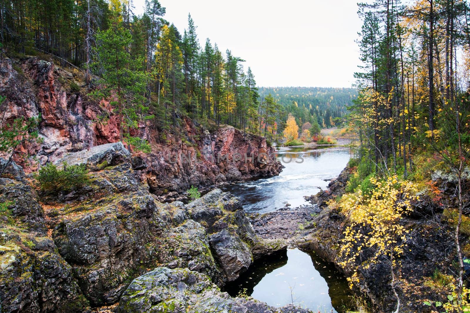 Rocku coast of river covered by autumn forest