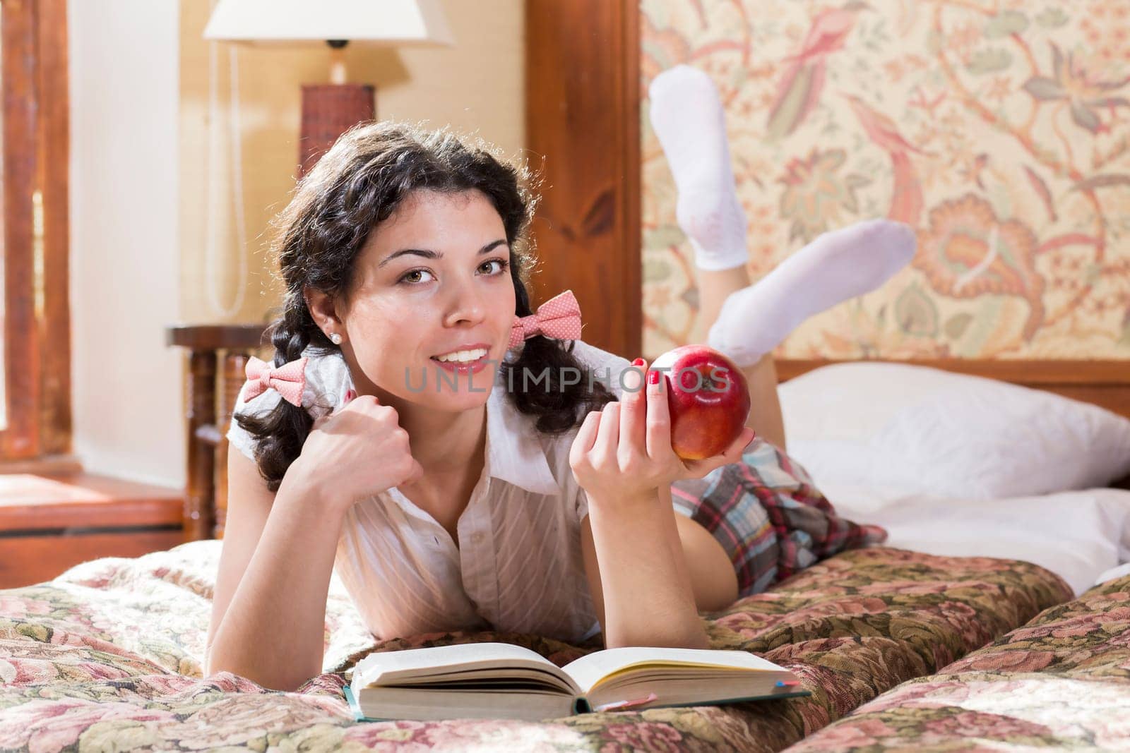 Woman in schoolgirl dress eat apple while read