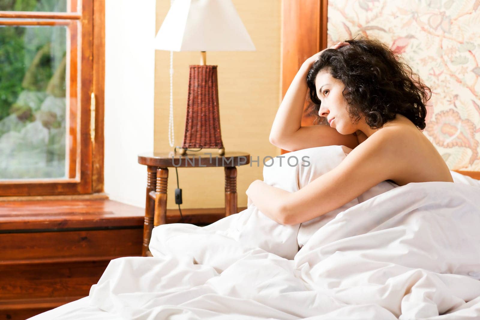 Woman under soft cover scratching her curly head