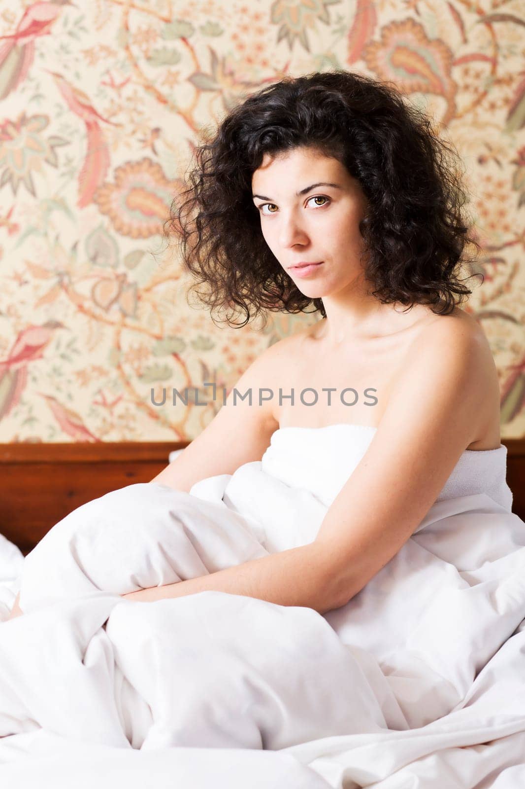 Woman under soft cover seems serious of something