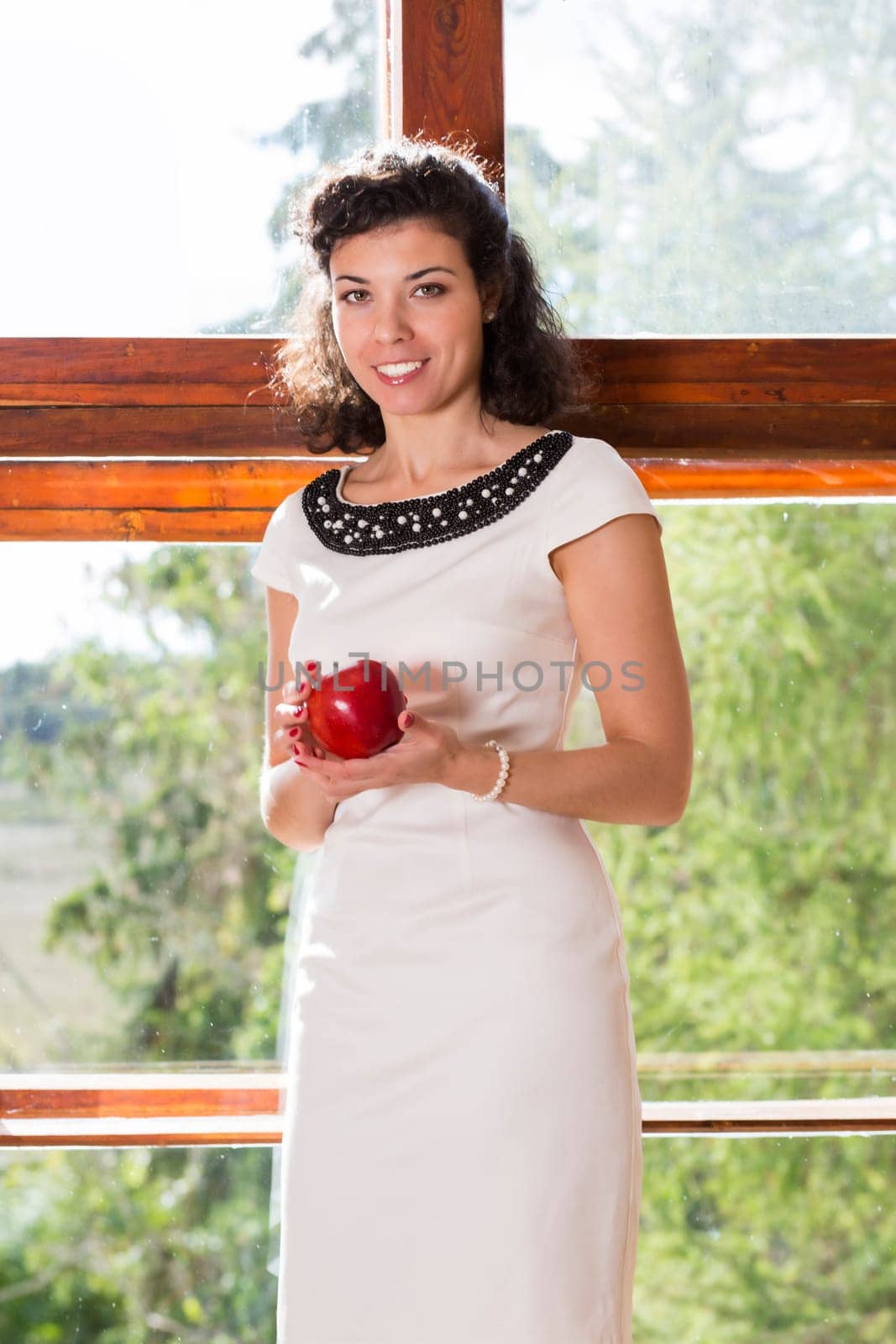 Pretty woman on sill smile and hold apple