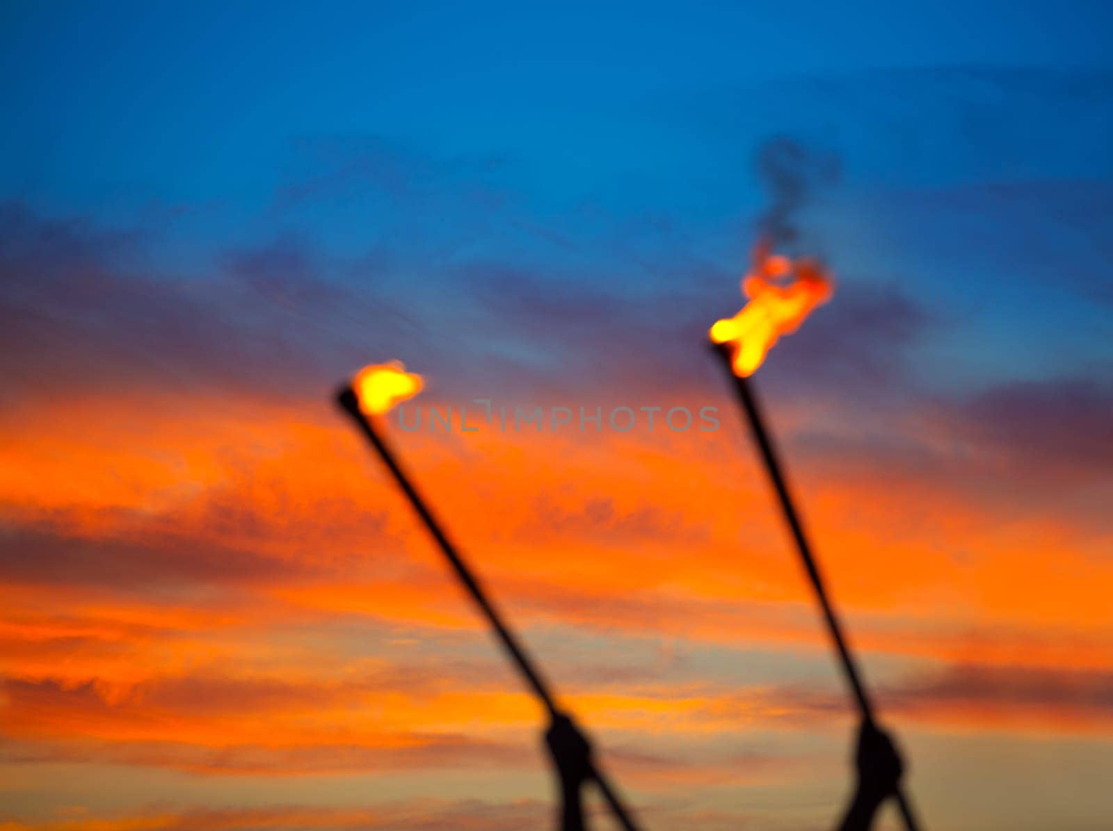 Fire torch at sunset sky with red clouds background