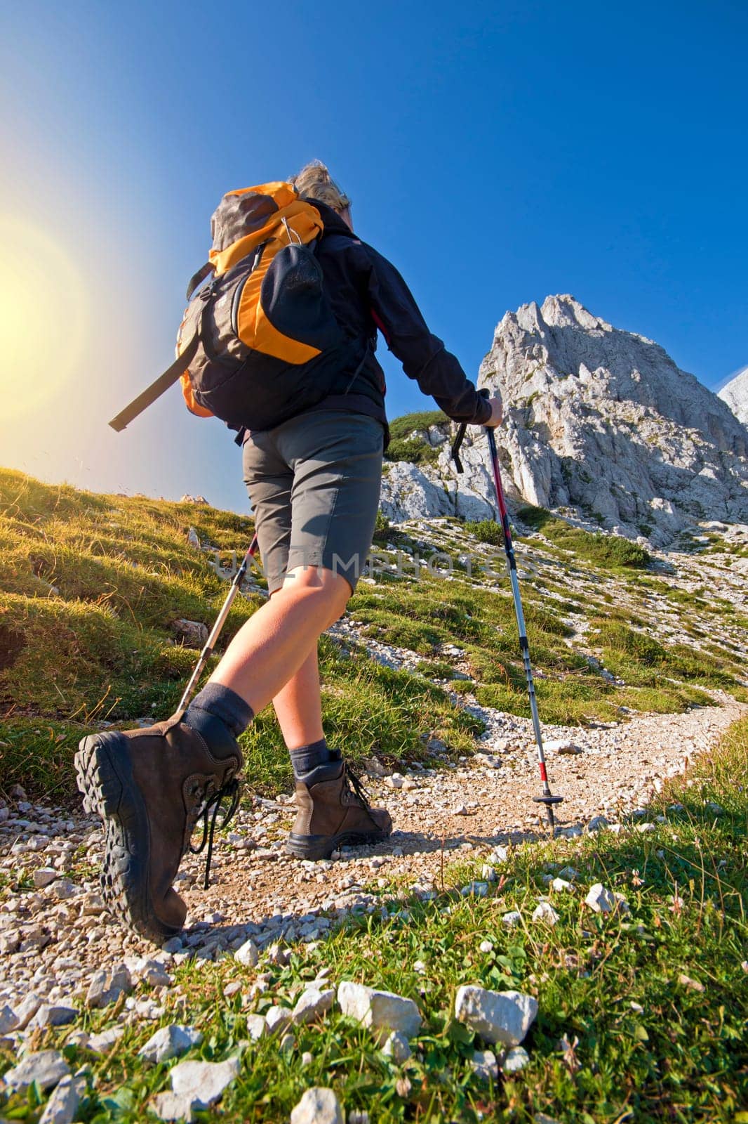 Young woman on a sunny day hiking in high mountains