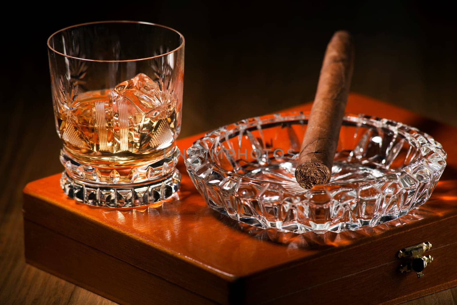 Whiskey and cigar on wooden box close up