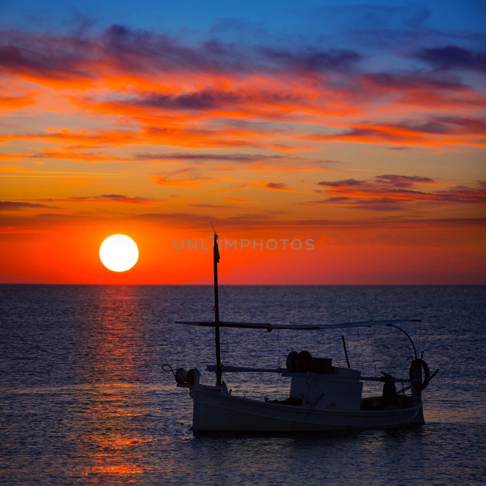Ibiza sunset  view and menorquina fisherboat from Formentera orange sky