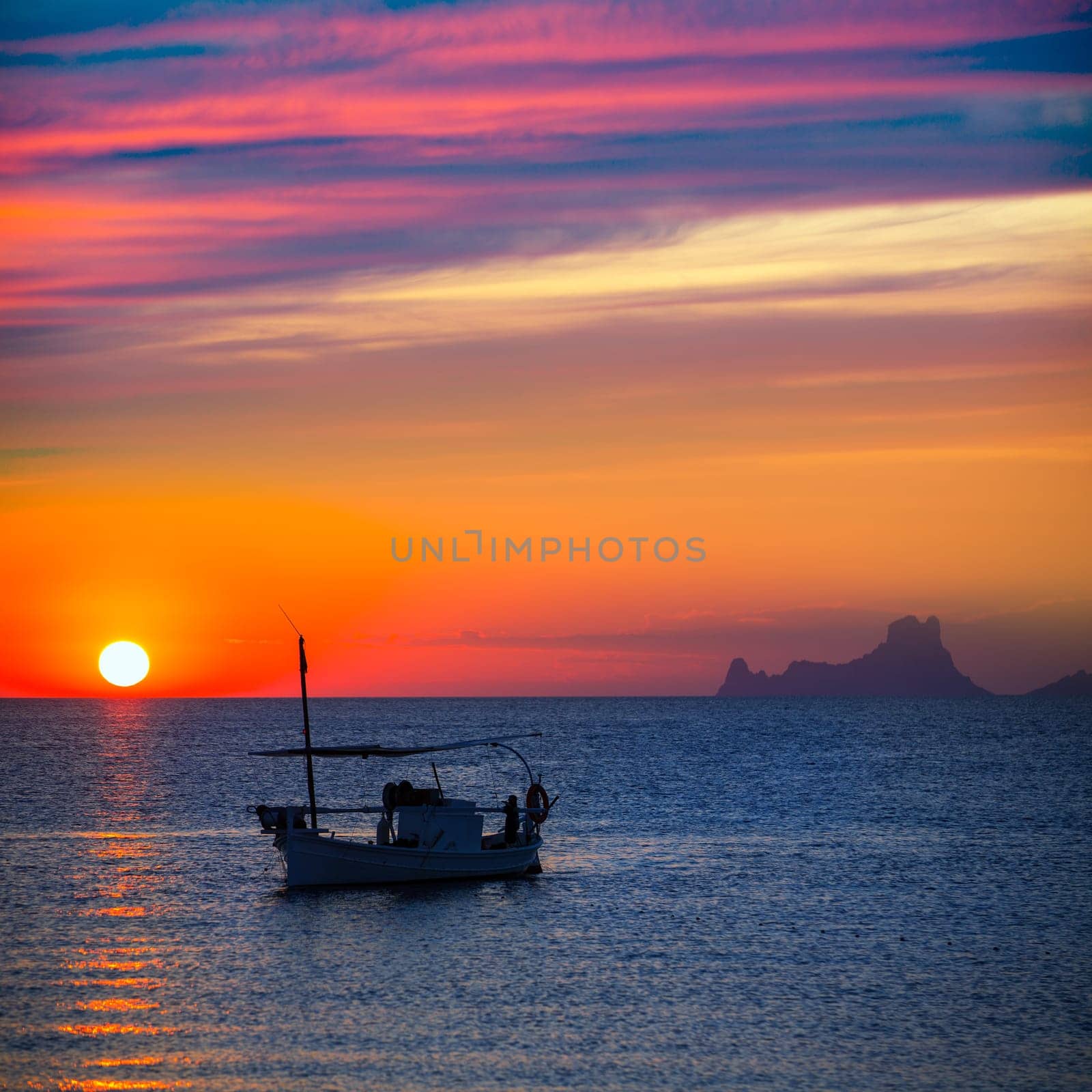 Ibiza sunset Es Vedra view and menorquina fisherboat from Formentera orange sky