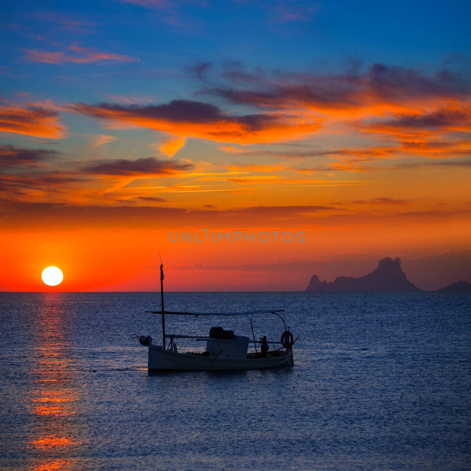 Ibiza sunset Es Vedra view and menorquina fisherboat from Formentera orange sky
