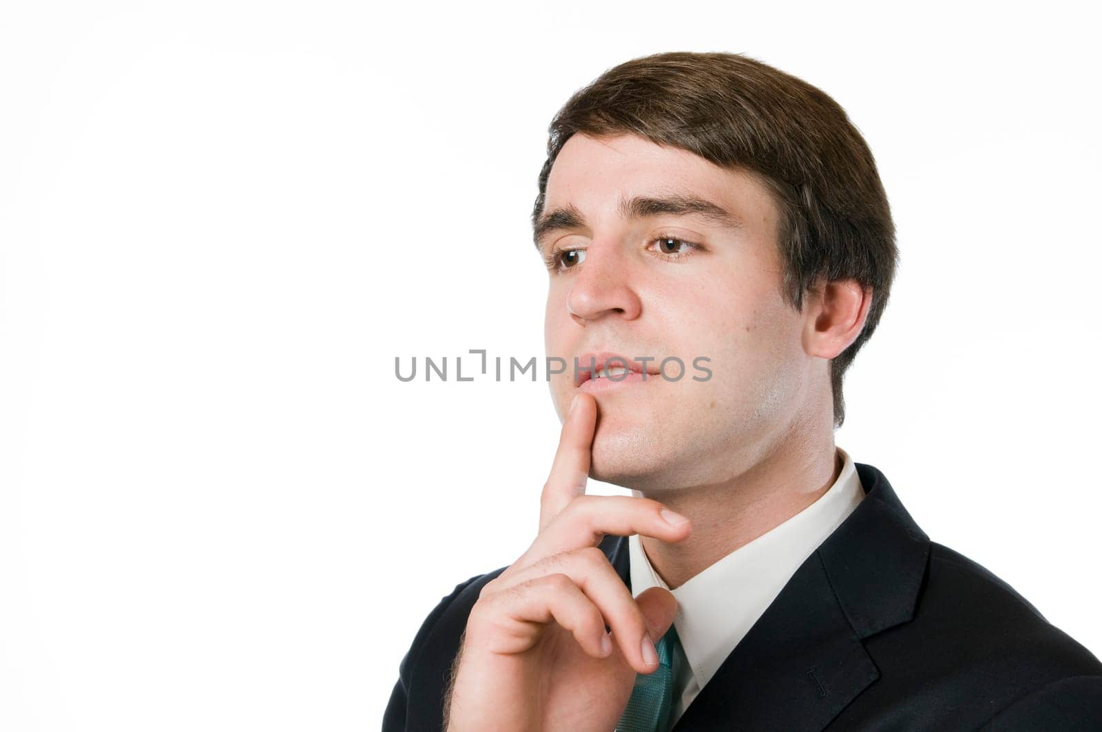 Head-and-shoulder portrait of a young man in a black suit looking thoughtfully with his index finger to his mouth