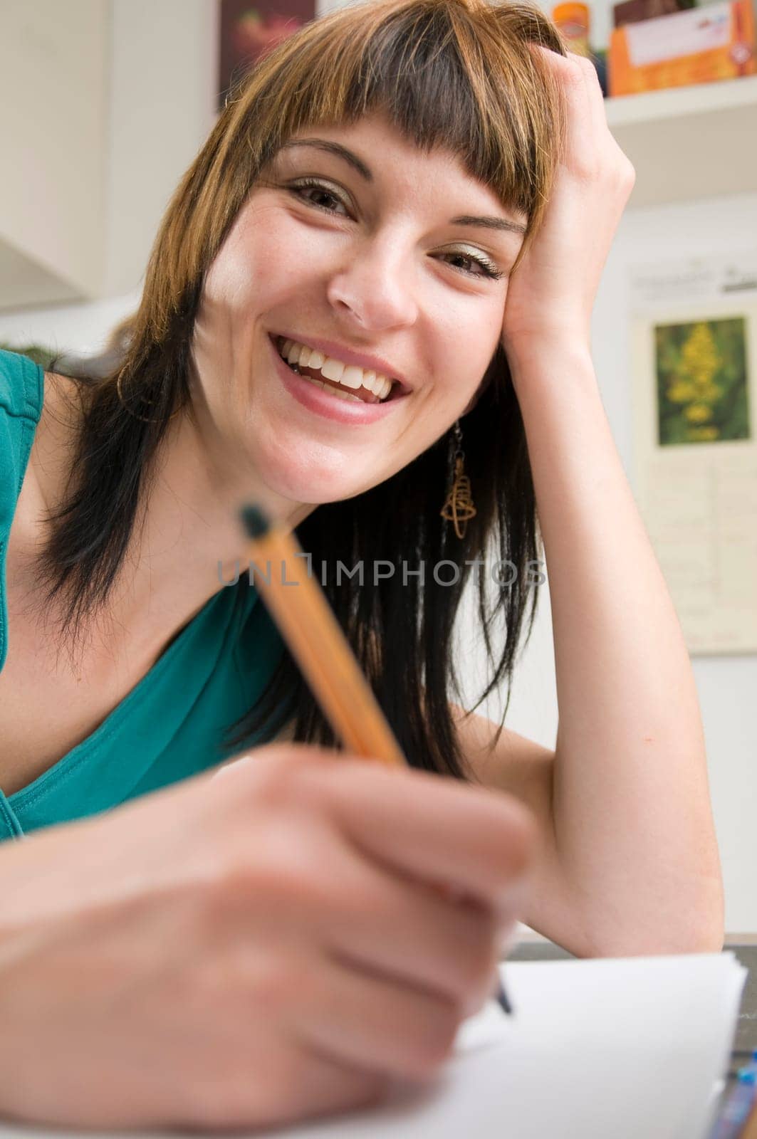 Head-and-shoulder view of a young,brunette woman sitting at the table with pen in hand and binder in front of her