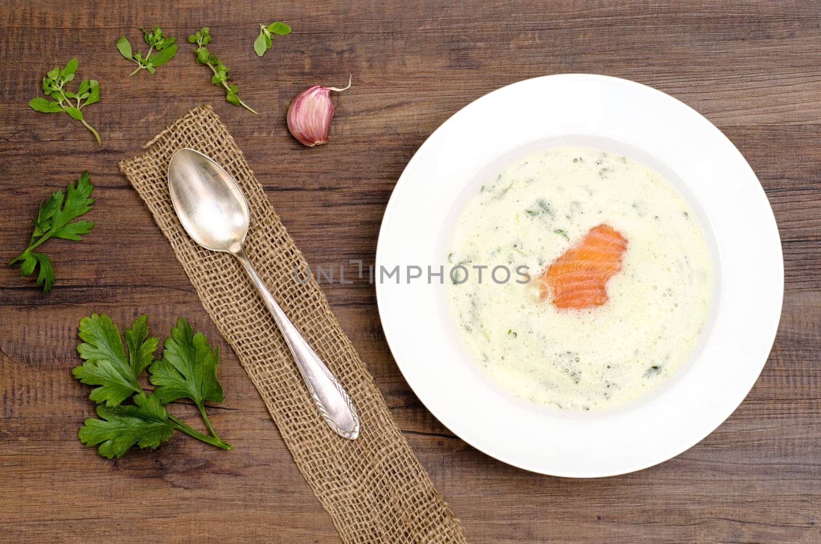 Frothy herb soup with salmon in a white plate