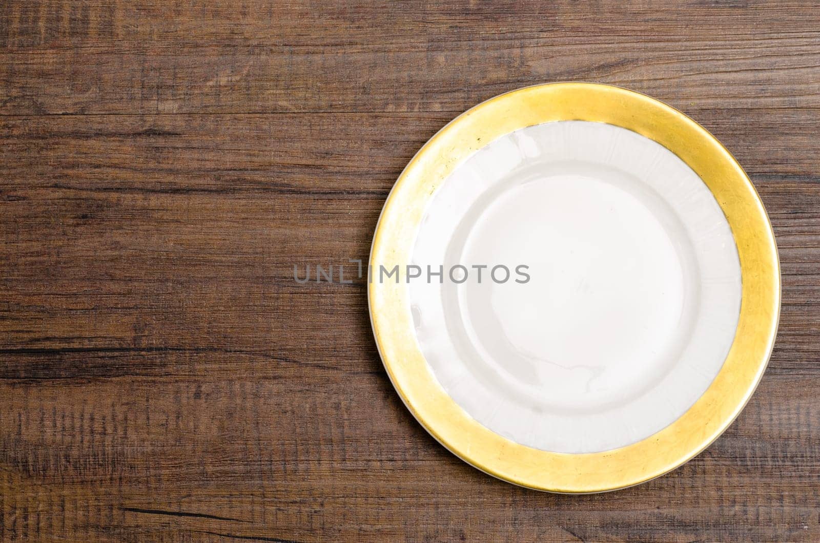 Plate with golden rim on wooden table