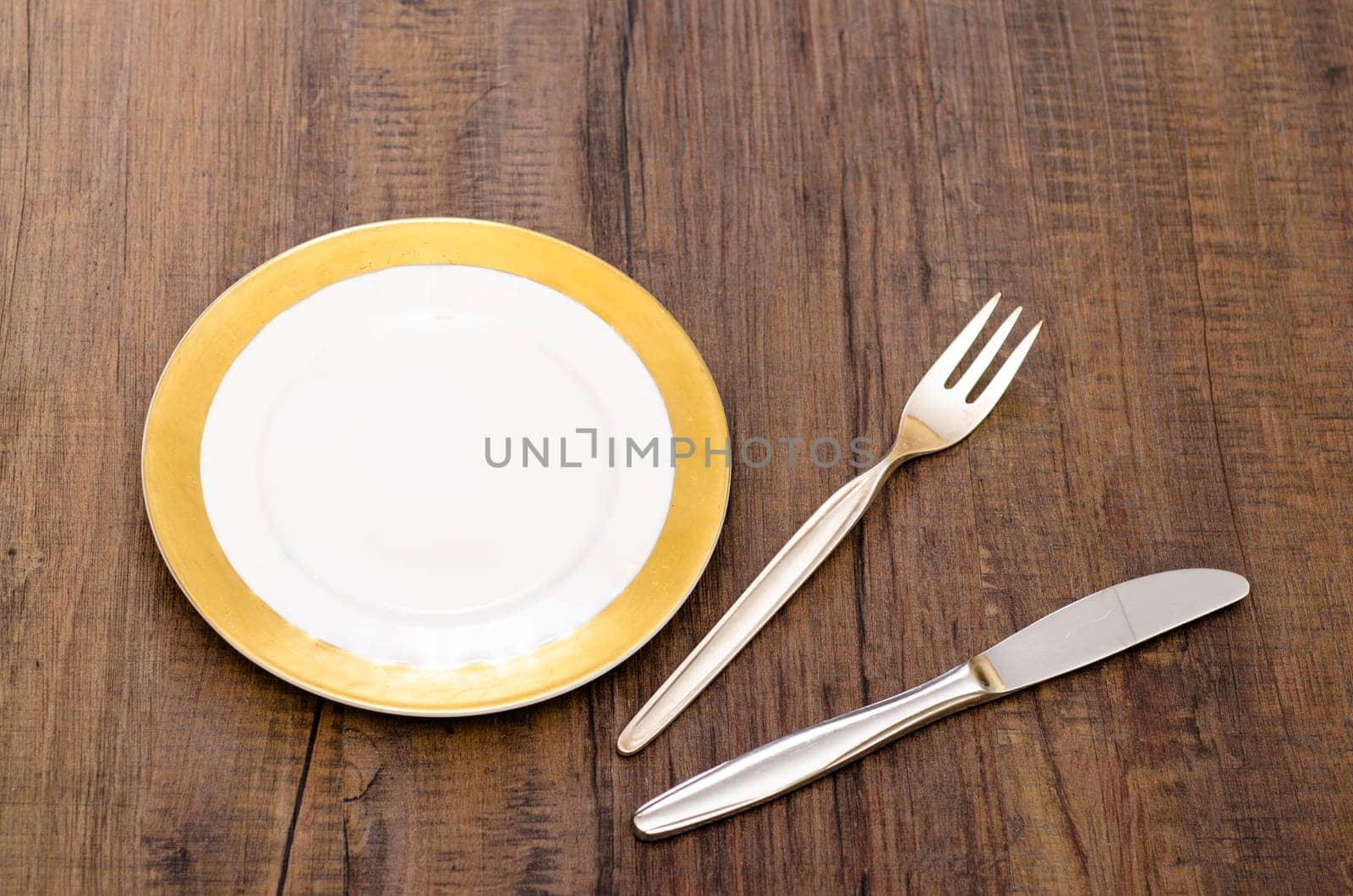 Place setting consisting of plate,knife and fork on a dining table