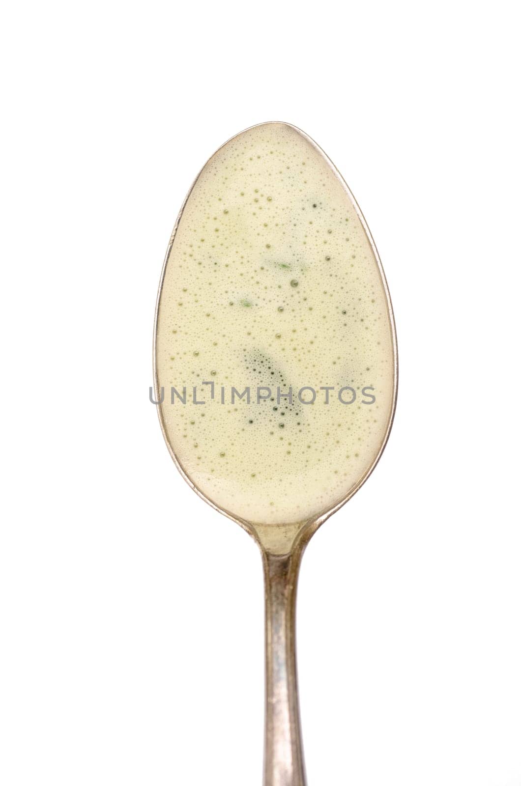 Spoon with foam of green herb soup with marjoram