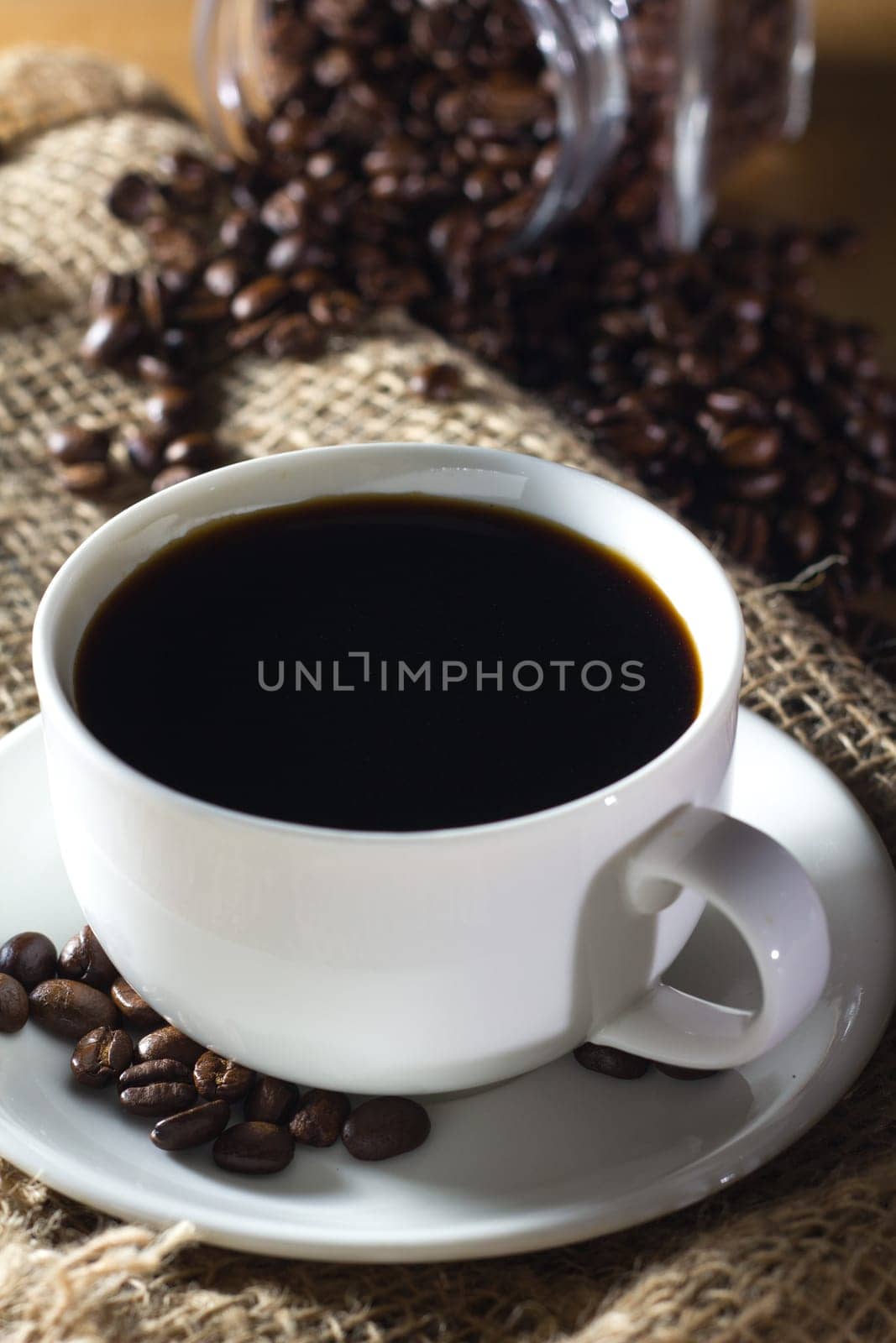 Black roasted coffee beans in a small burlap sack