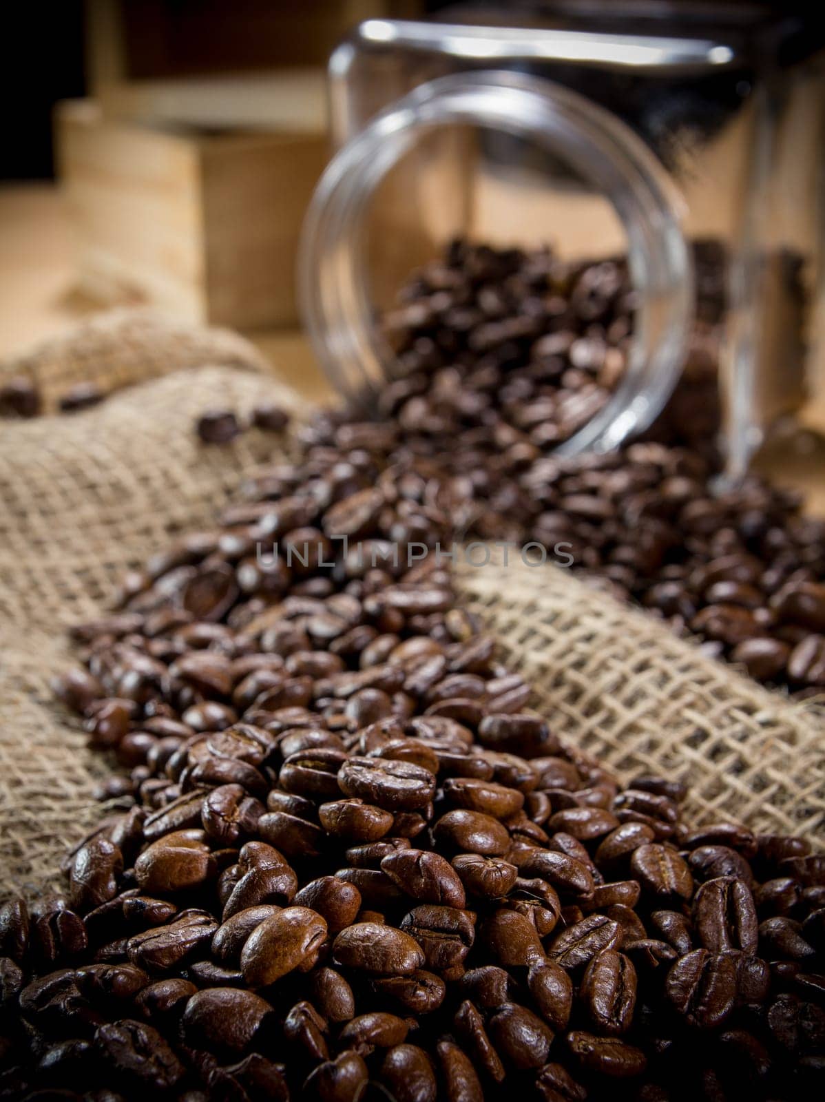 Black roasted coffee beans in a small burlap sack