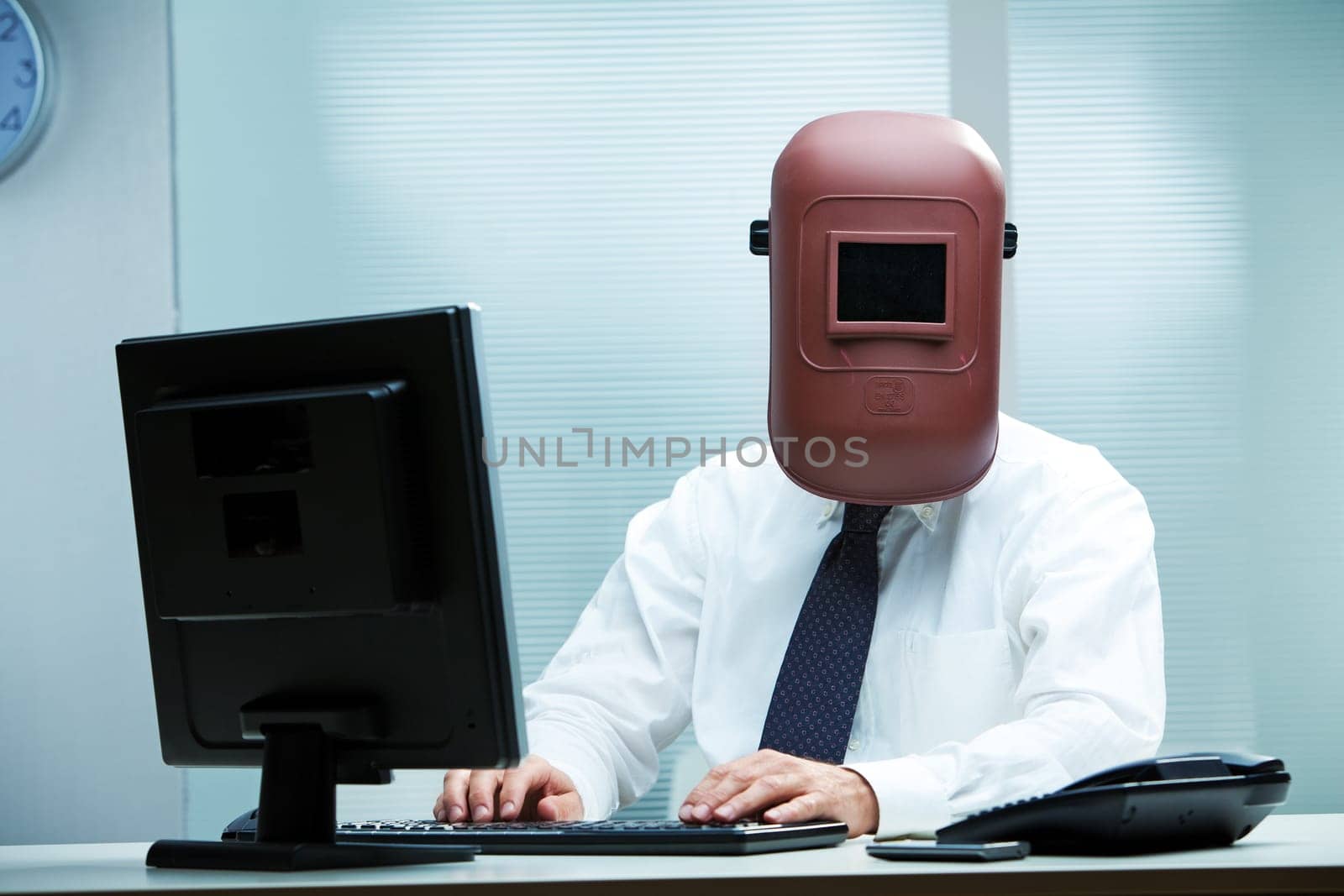 An office worker at his desk wearing a welder's mask