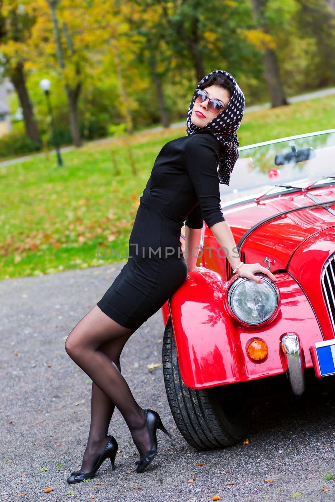Woman in black posing on red car front